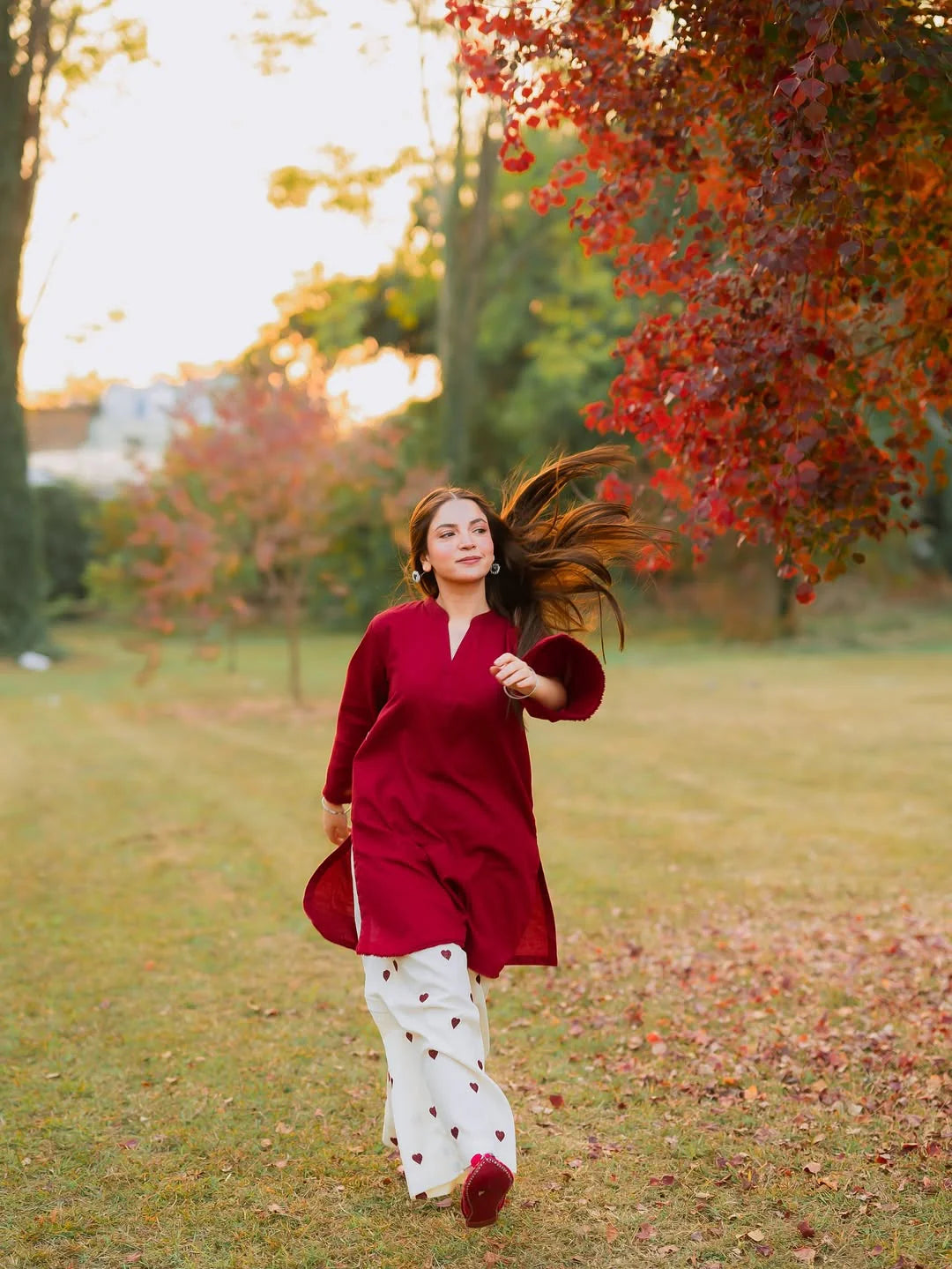 Woman in a red outfit running in a park with autumn leaves